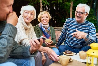 Senioren genießen die gemeinsame Zeit im Freien beim Essen und feiern