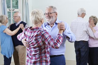 Eine Gruppe Senioren tanzen als Pärchen bei einem Tanzkurs